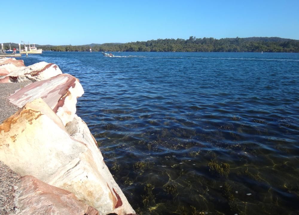 A Large Body of Water With a Boat in the Distance — Headlands Glass in Bangalow, NSW